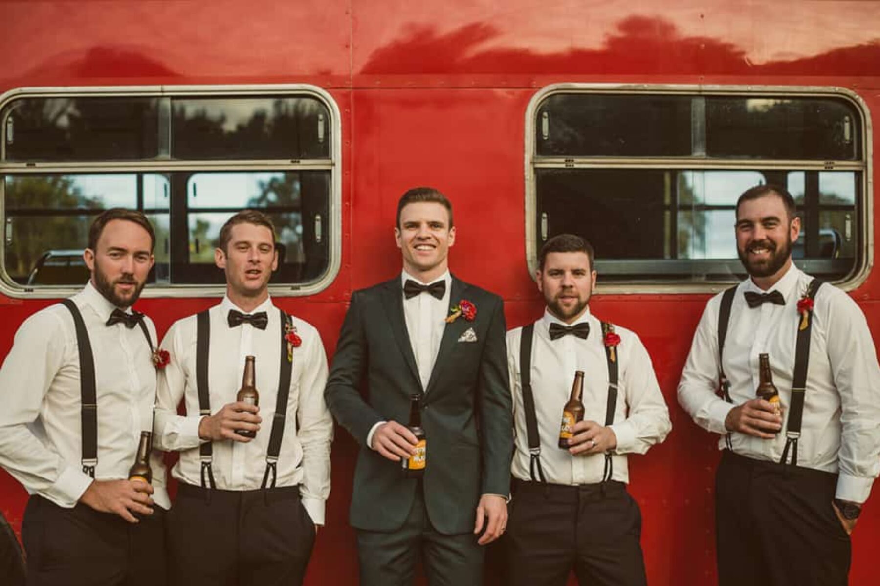 groom and groomsmen by red double decker wedding bus
