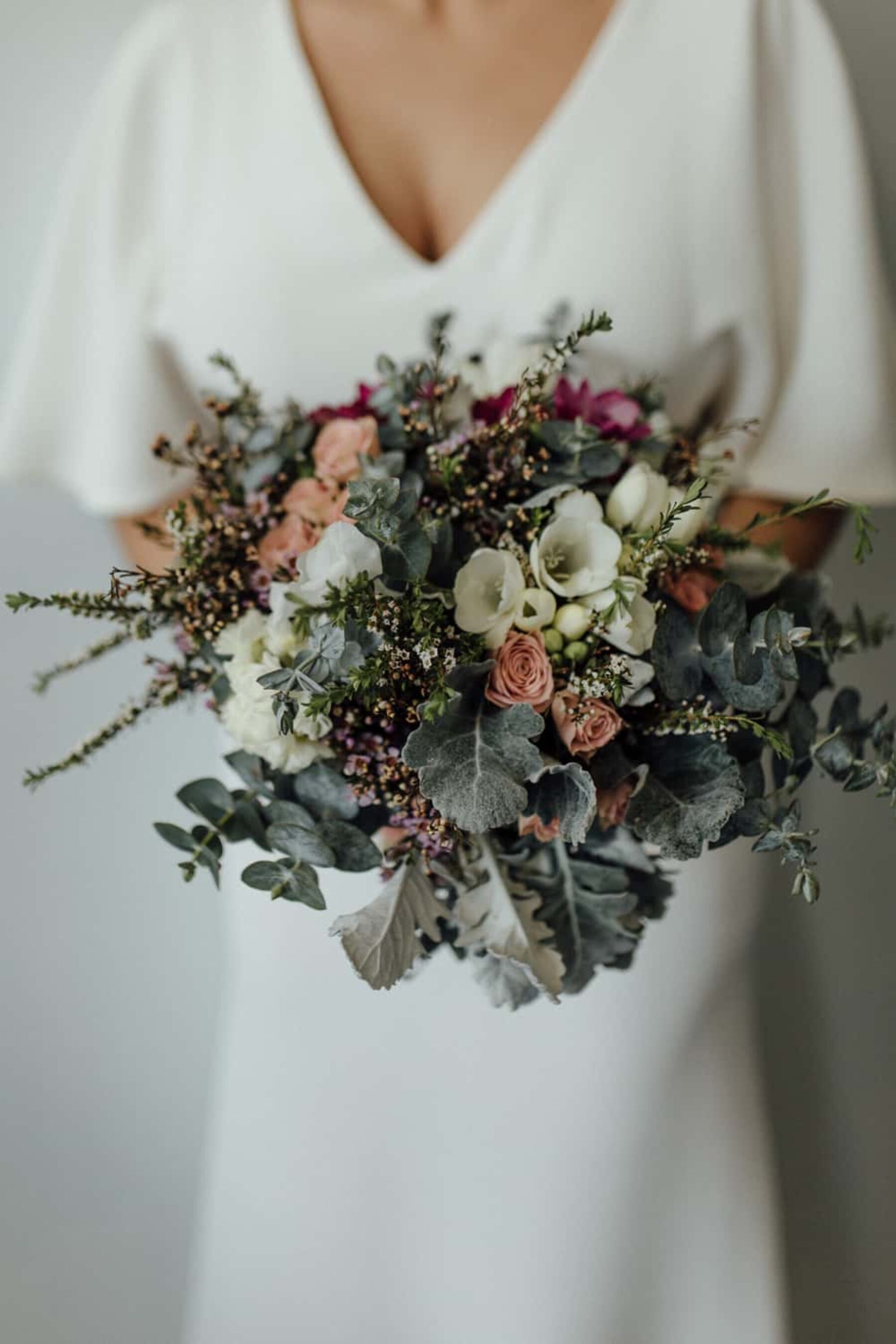 modern bride with rose and wax flower bouquet in muted tones