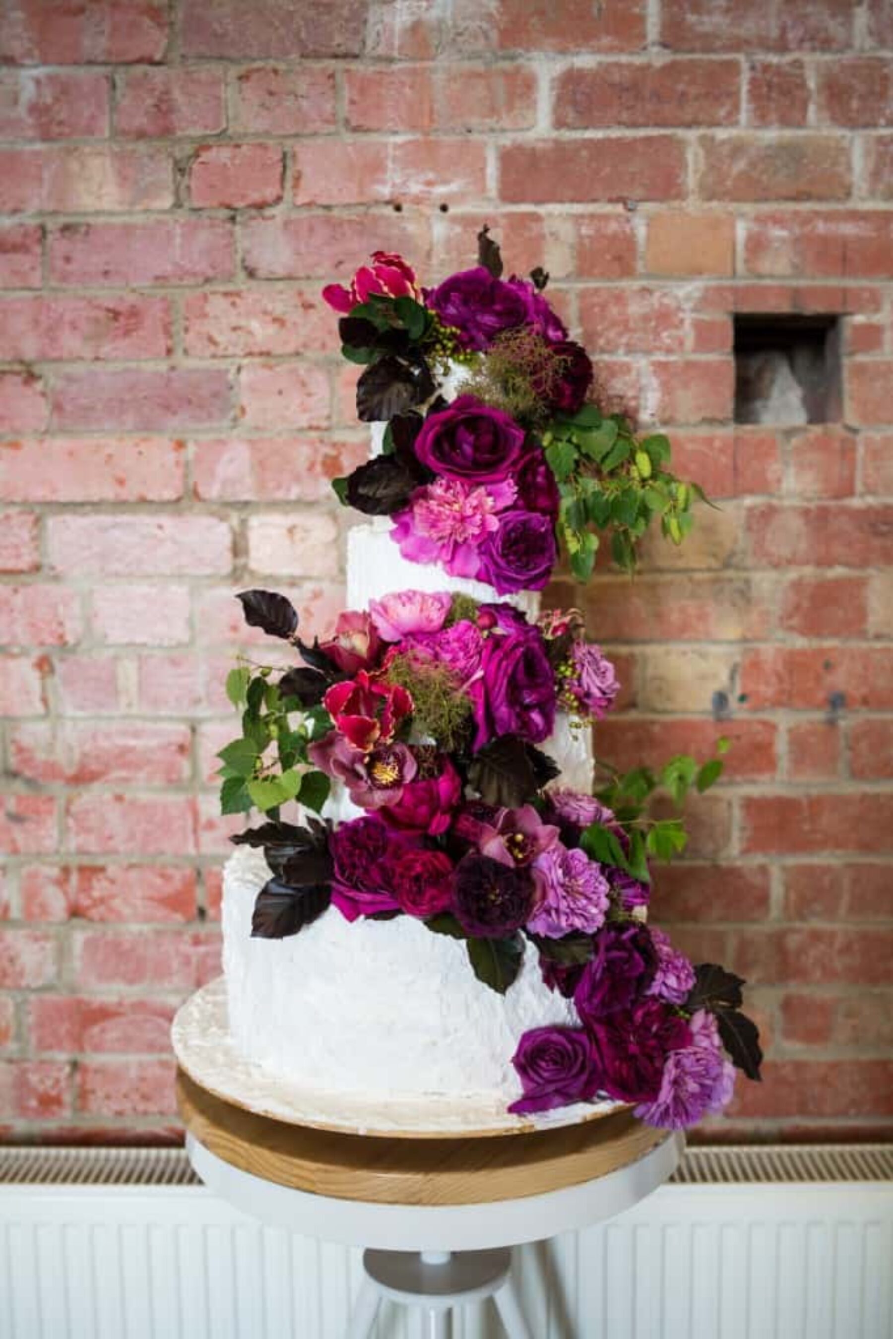 3 tiered wedding cake with fresh magenta and plum flowers