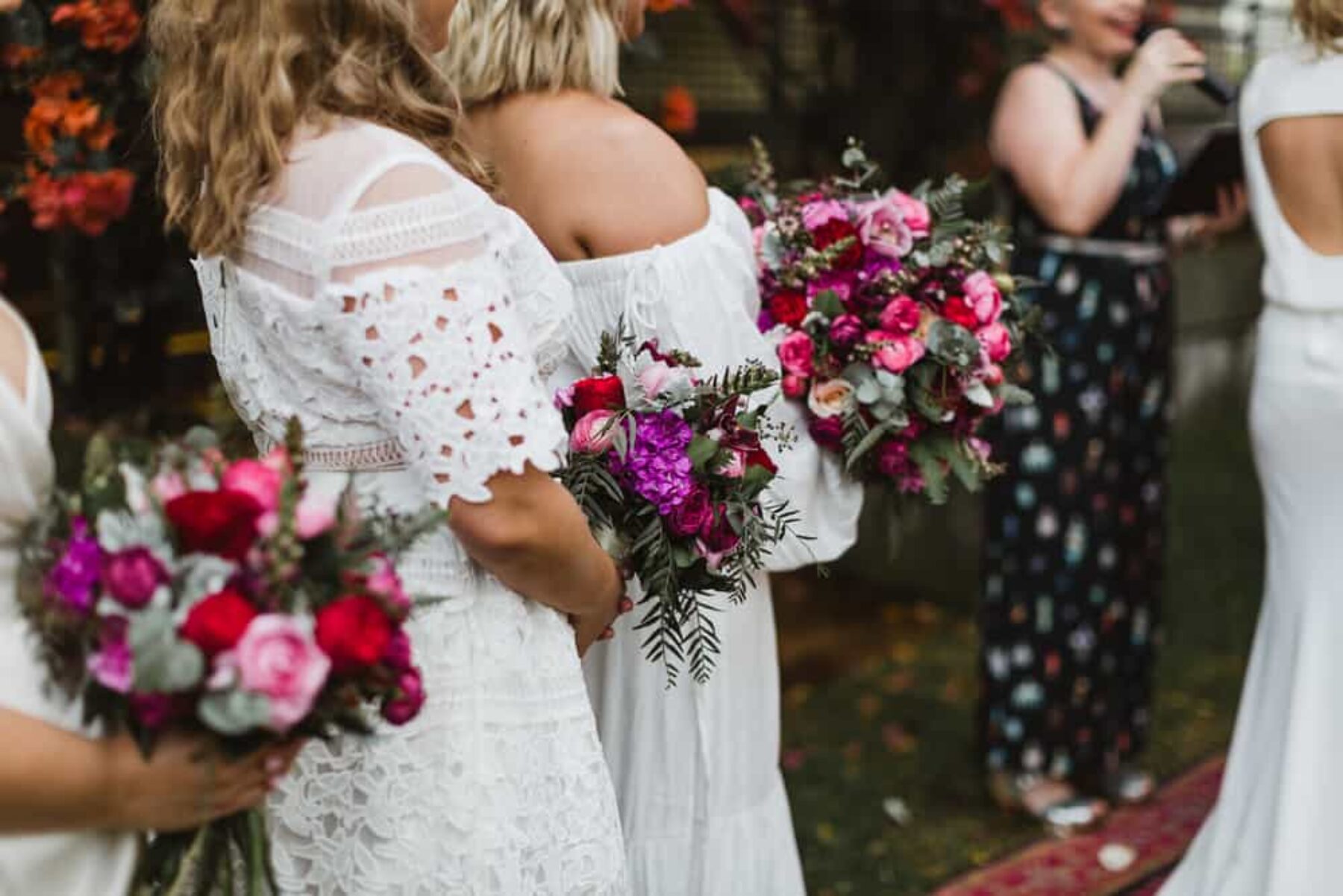 bridesmaids in white dresses with berry toned bouquets