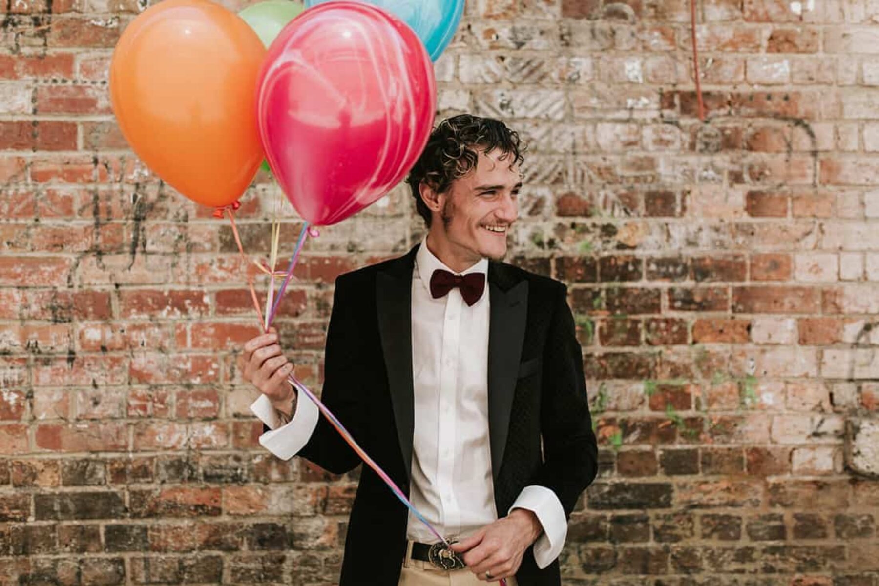 cute groom with colourful balloons