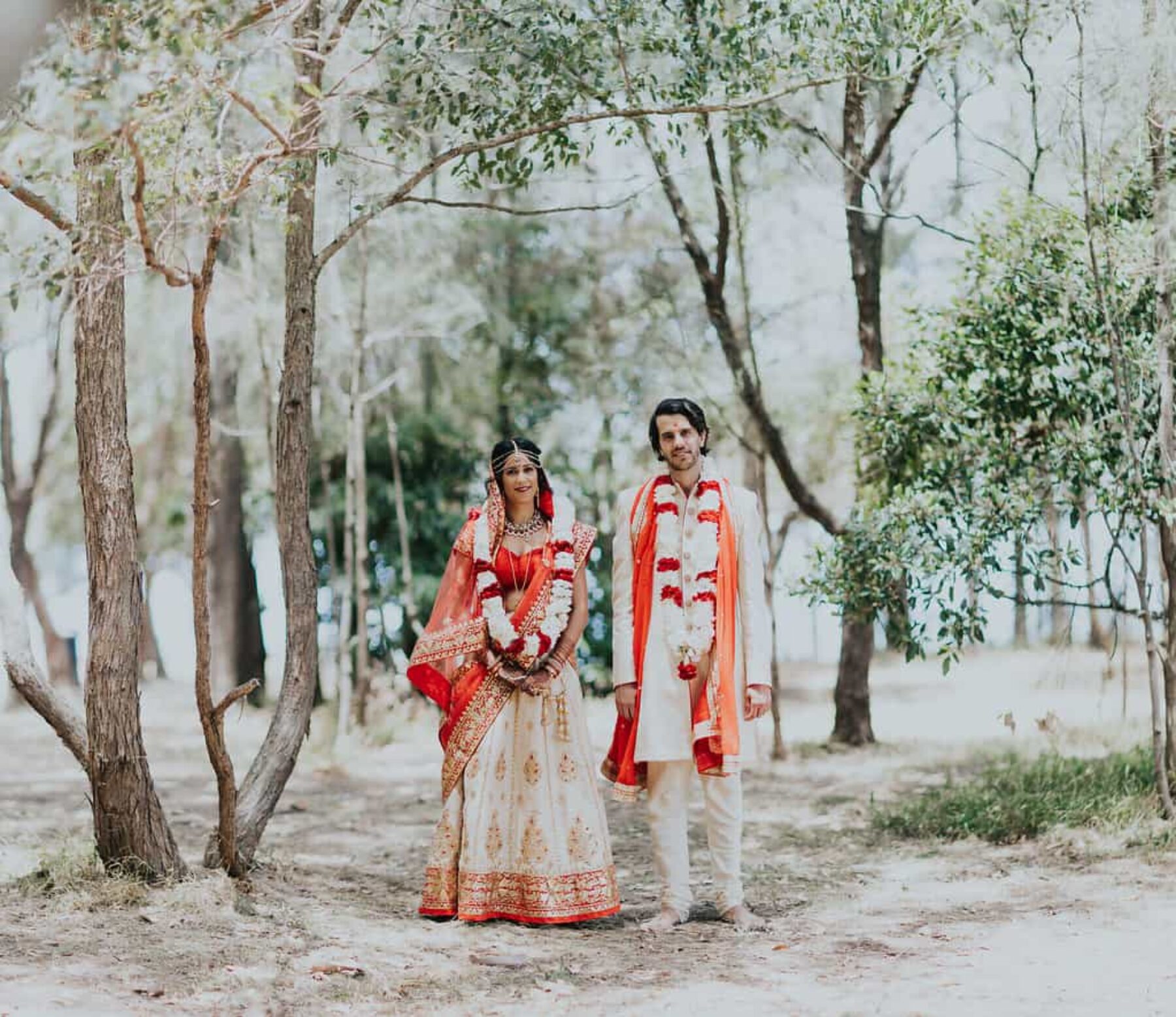 Hindu bride and groom in vibrant red and gold wedding attire - Nina Claire Photography
