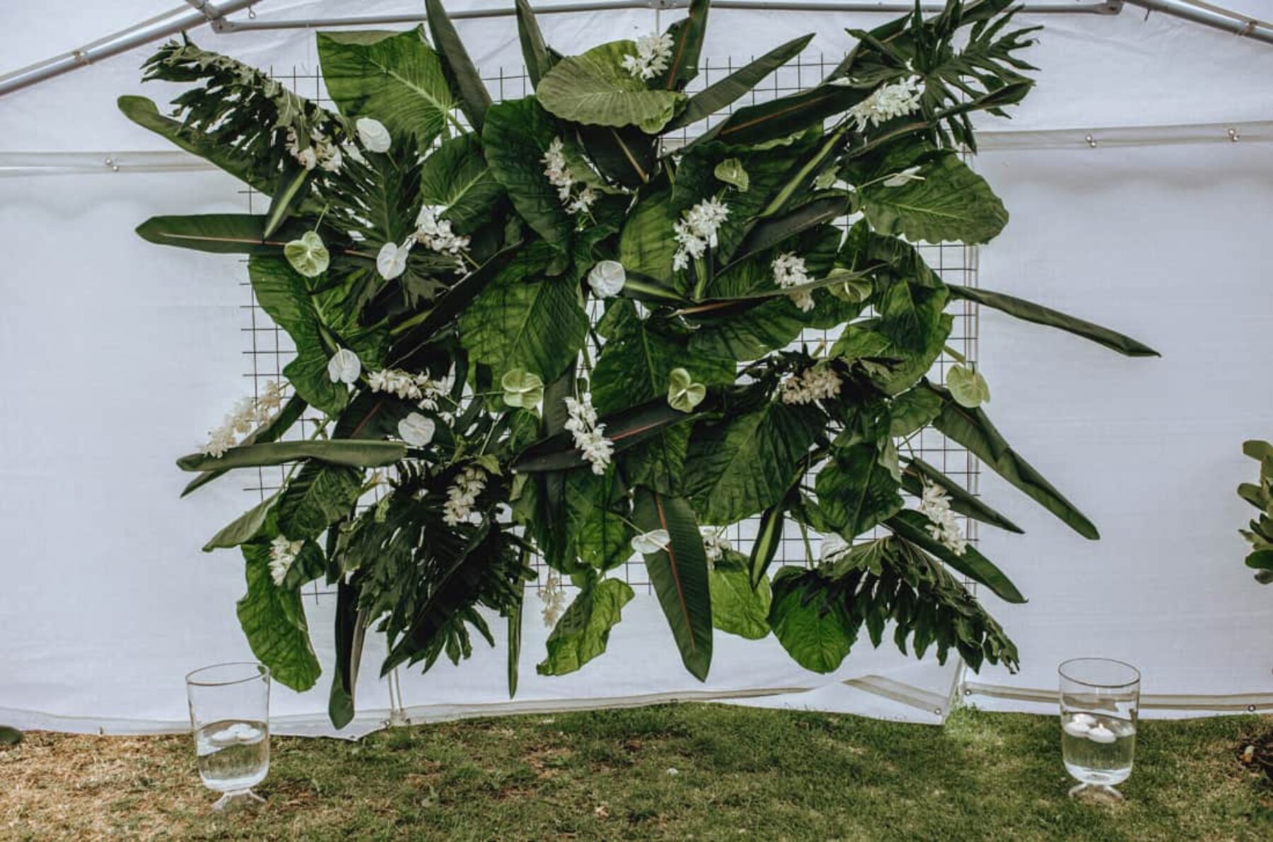 DIY greenery wedding backdrop with tropical foliage