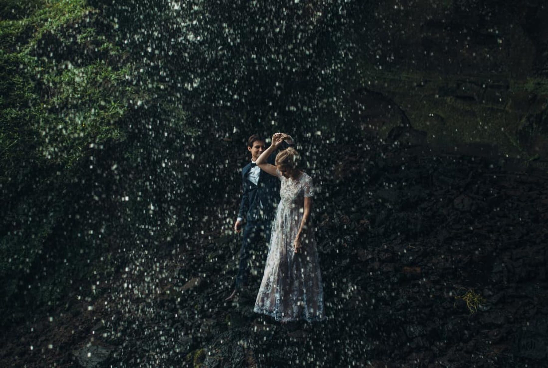 bride and groom dancing under waterfall