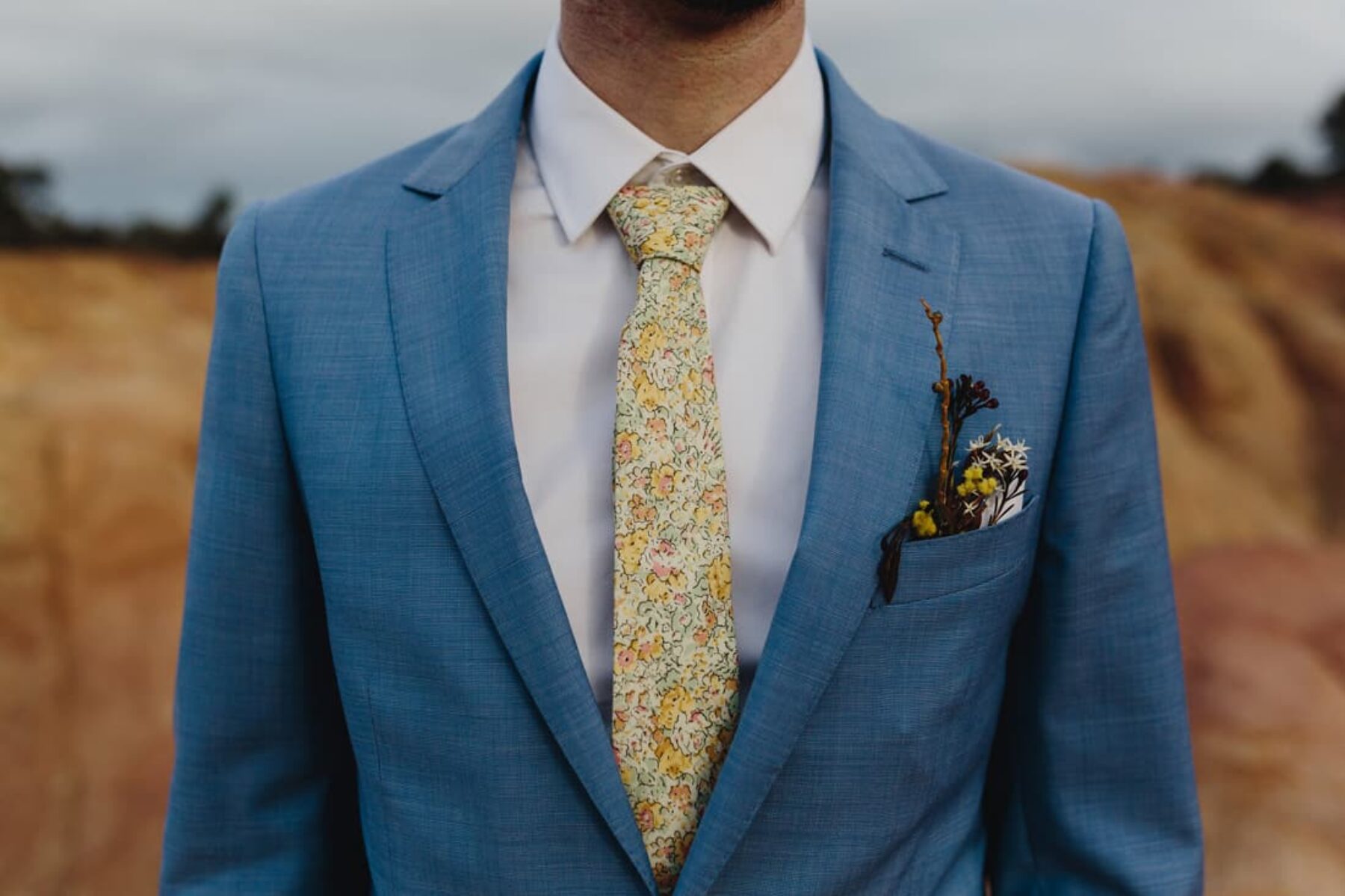 groom in blue blazer and yellow floral tie