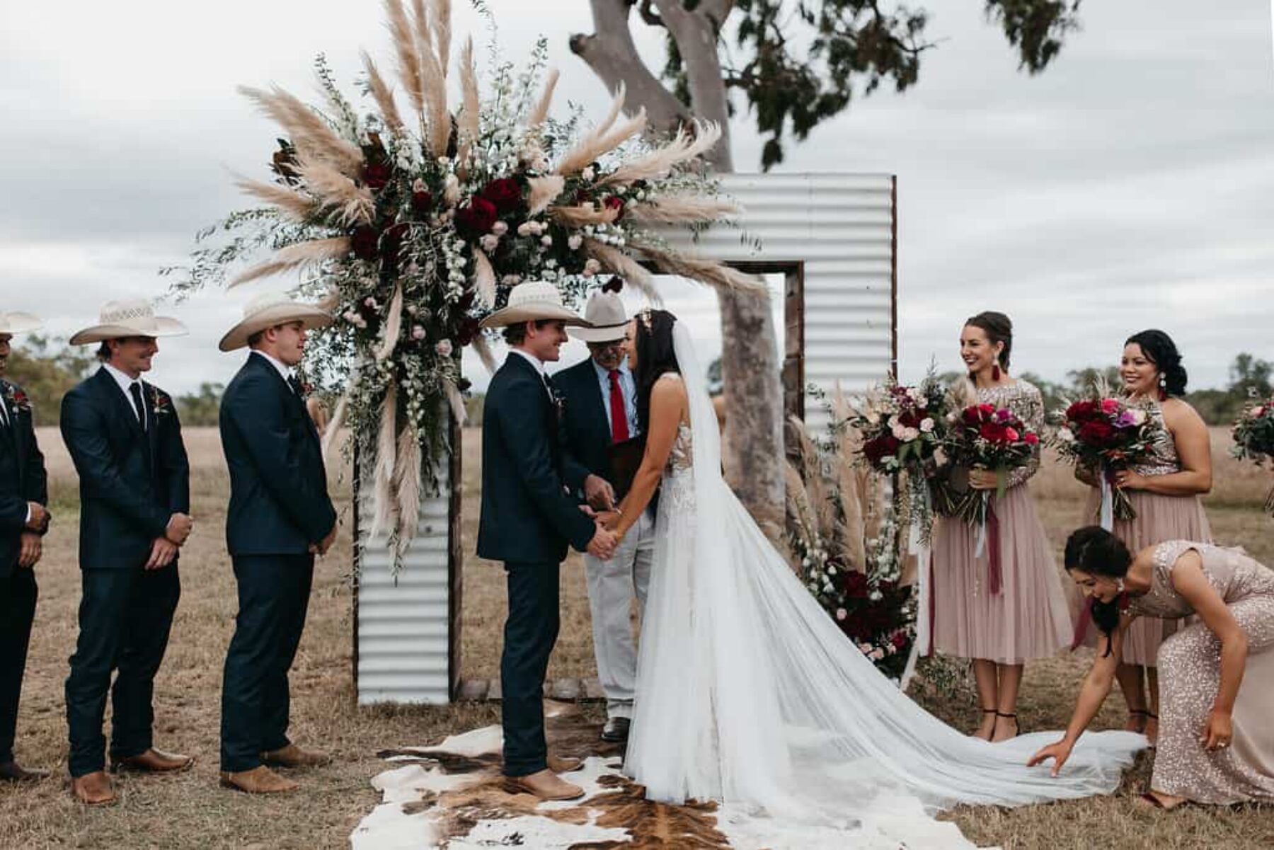 iron wedding arch with plumes of pampas grass and burgundy flowers