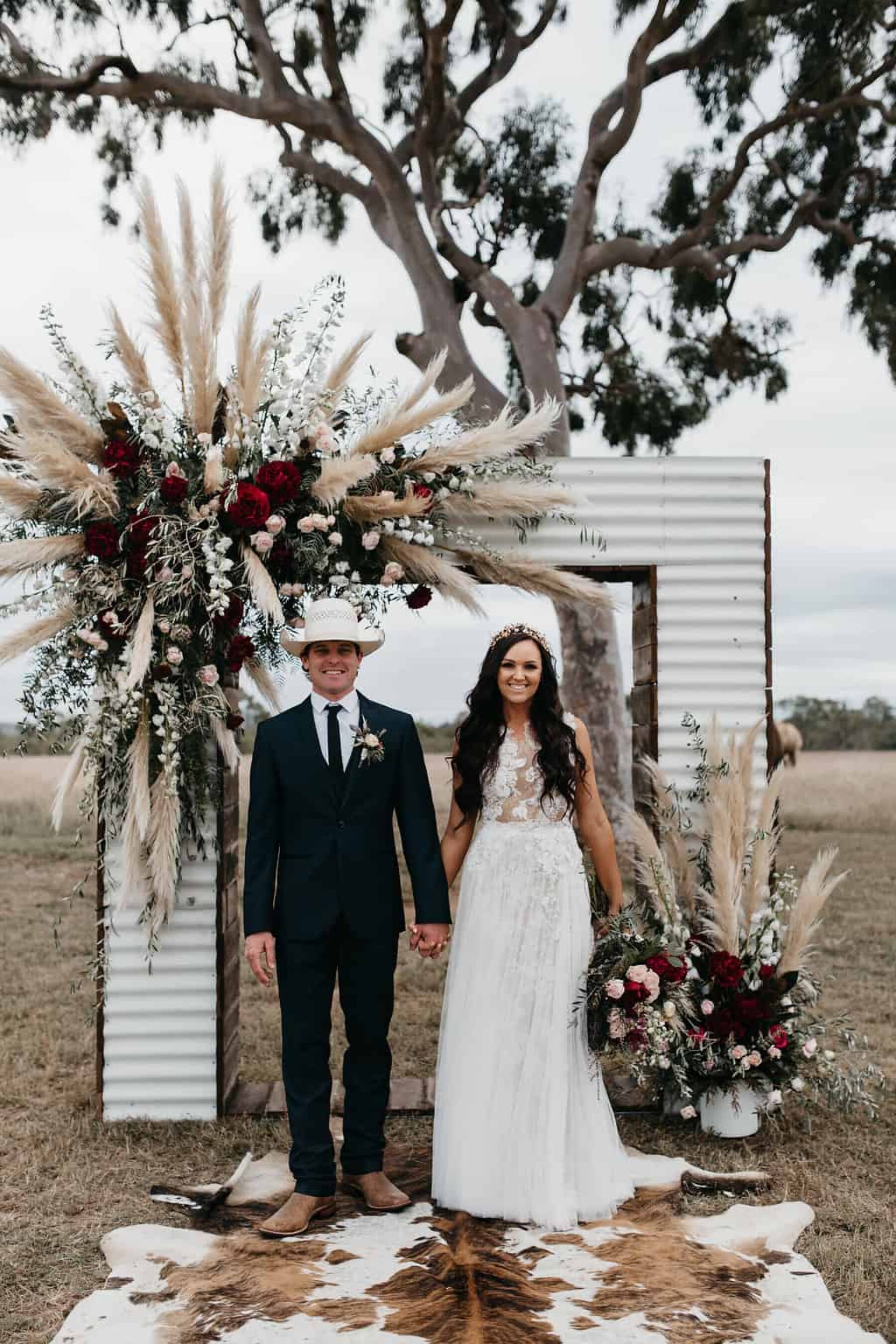 iron wedding arch with plumes of pampas grass and burgundy flowers