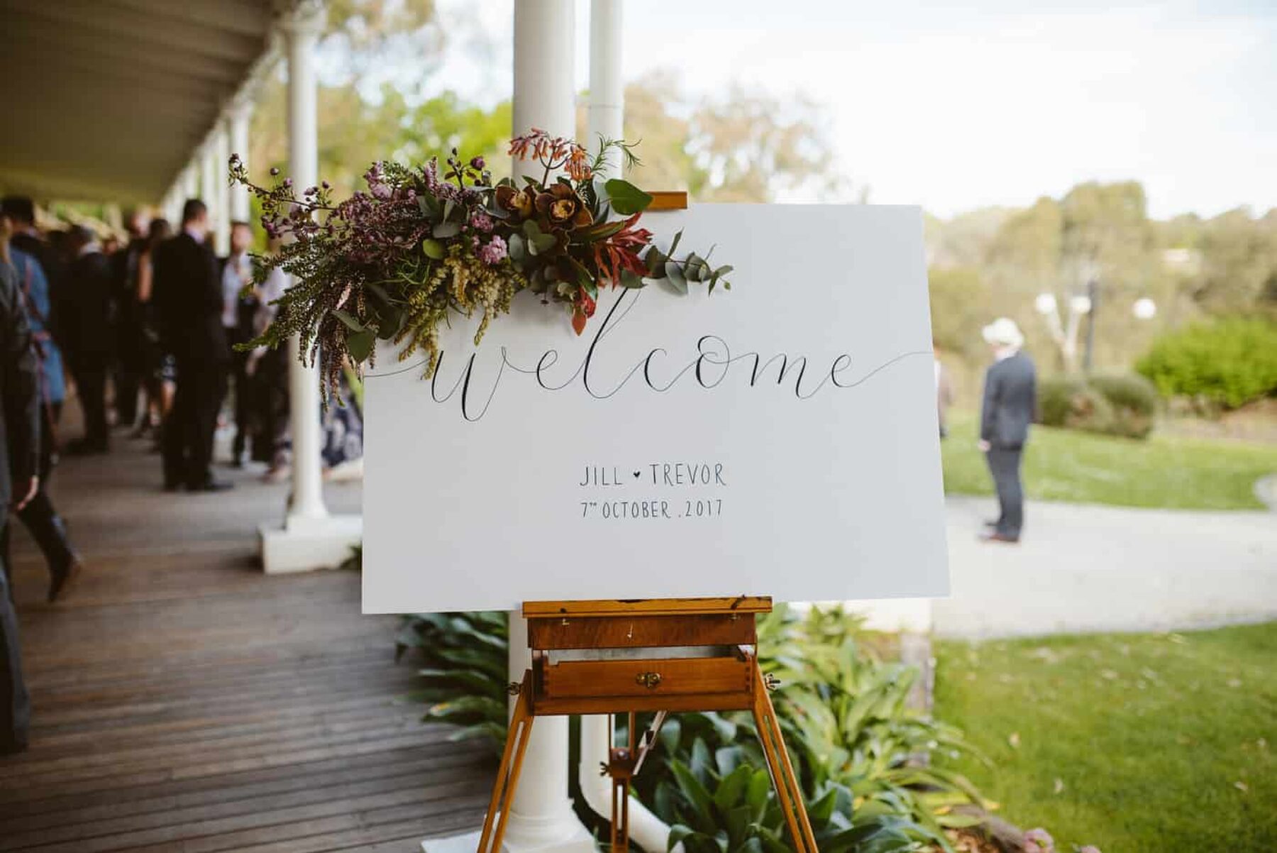 Calligraphy wedding welcome sign with floral arrangement