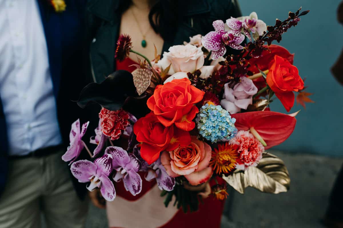 bold bridal bouquet with red roses, purple orchids and lotus pods