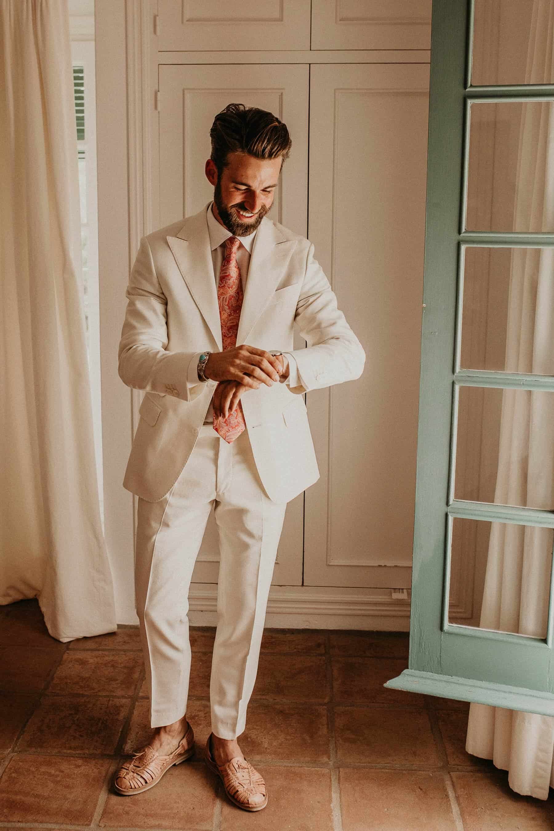 groom in white suit and leather sandals