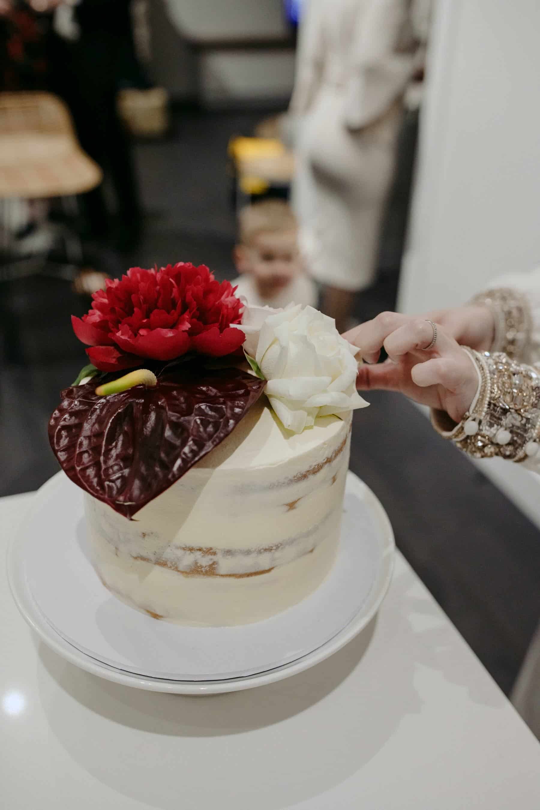 simple white cake with blush and burgundy flowers