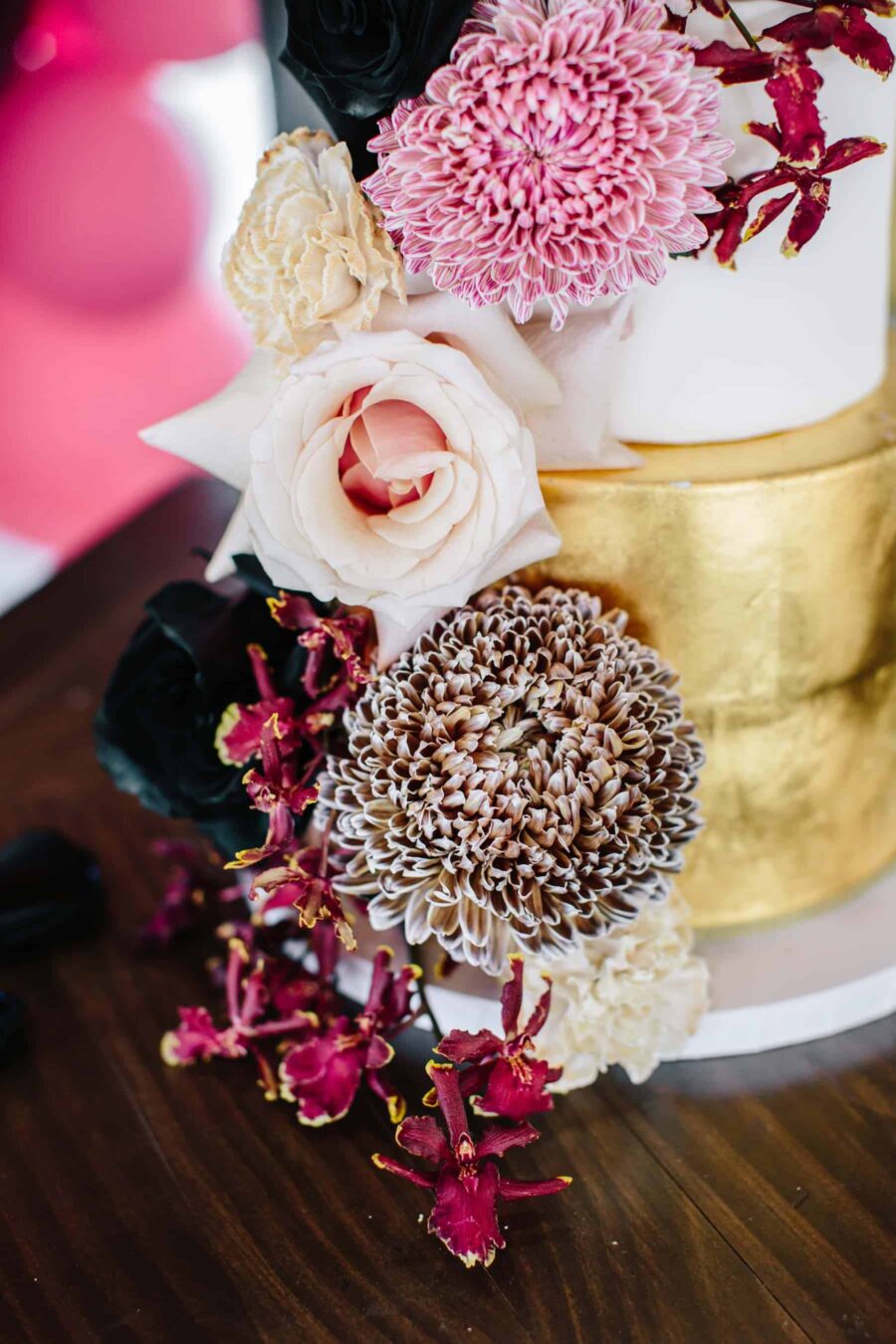 gold wedding cake with blush and burgundy flowers