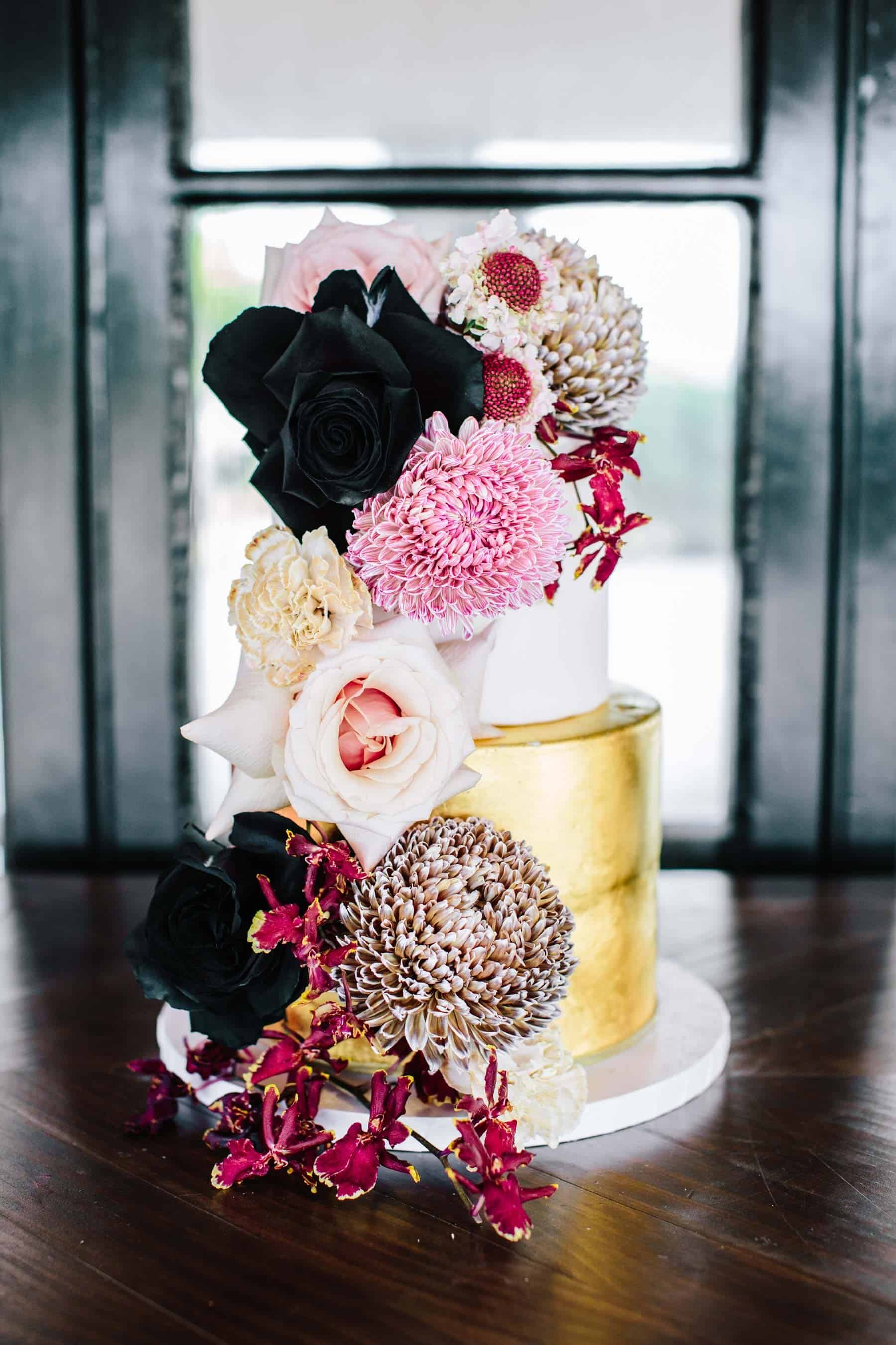 gold wedding cake with blush and burgundy flowers
