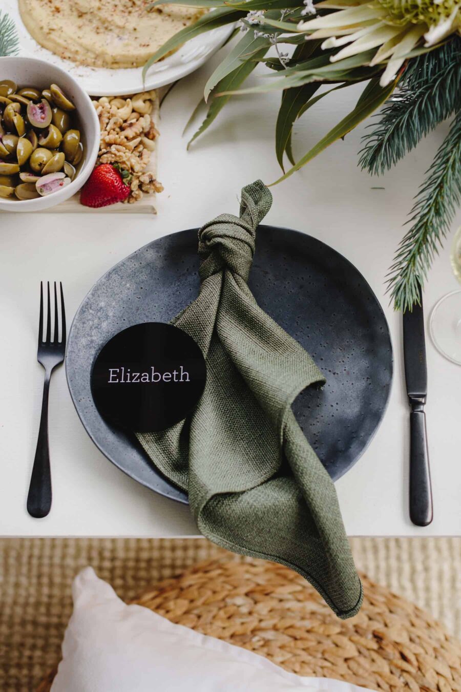 tied linen napkin on black plate with round acrylic place card