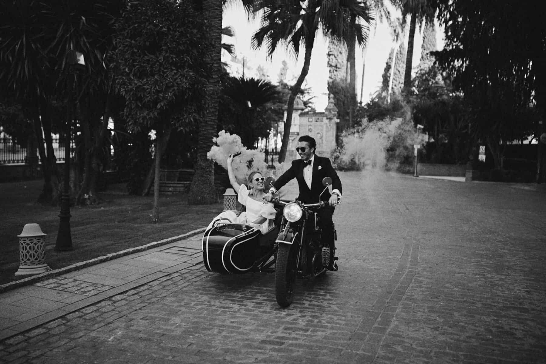 bride and groom on motorbike with smoke bombs