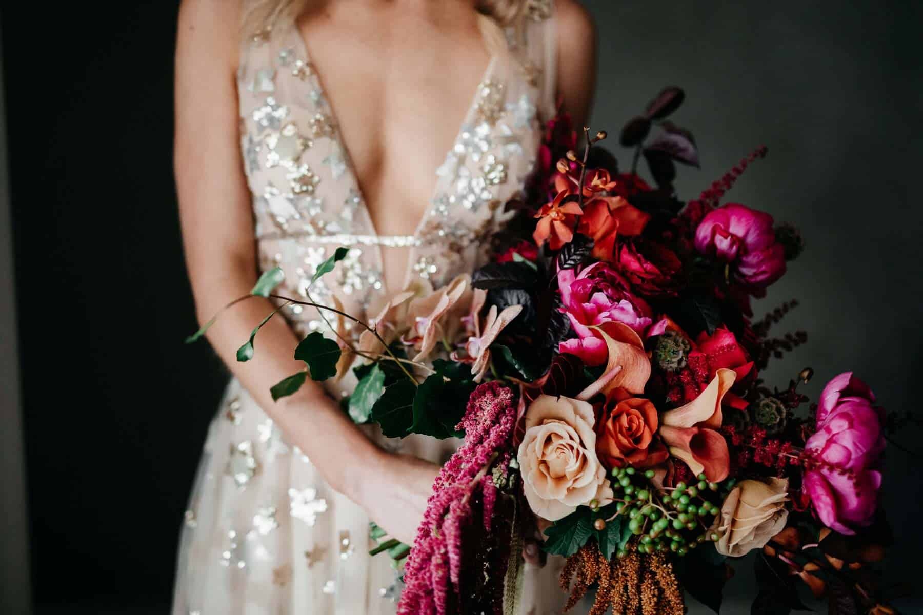 bride wears gold willowby by watters with gold amaroq crown and vibrant pink bouquet