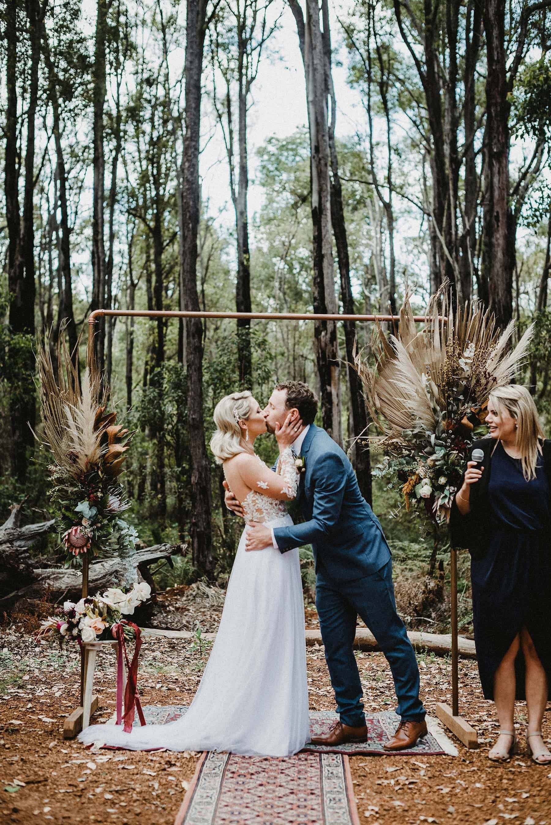 Paula & Jo bridal gown with groom's navy suit in forest wedding