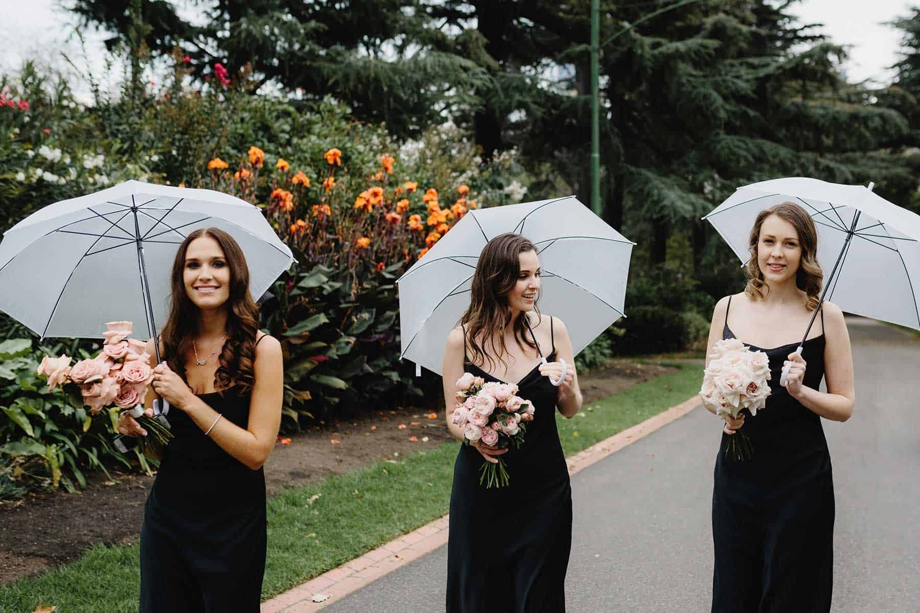 bridesmaids in black dresses with umbrellas