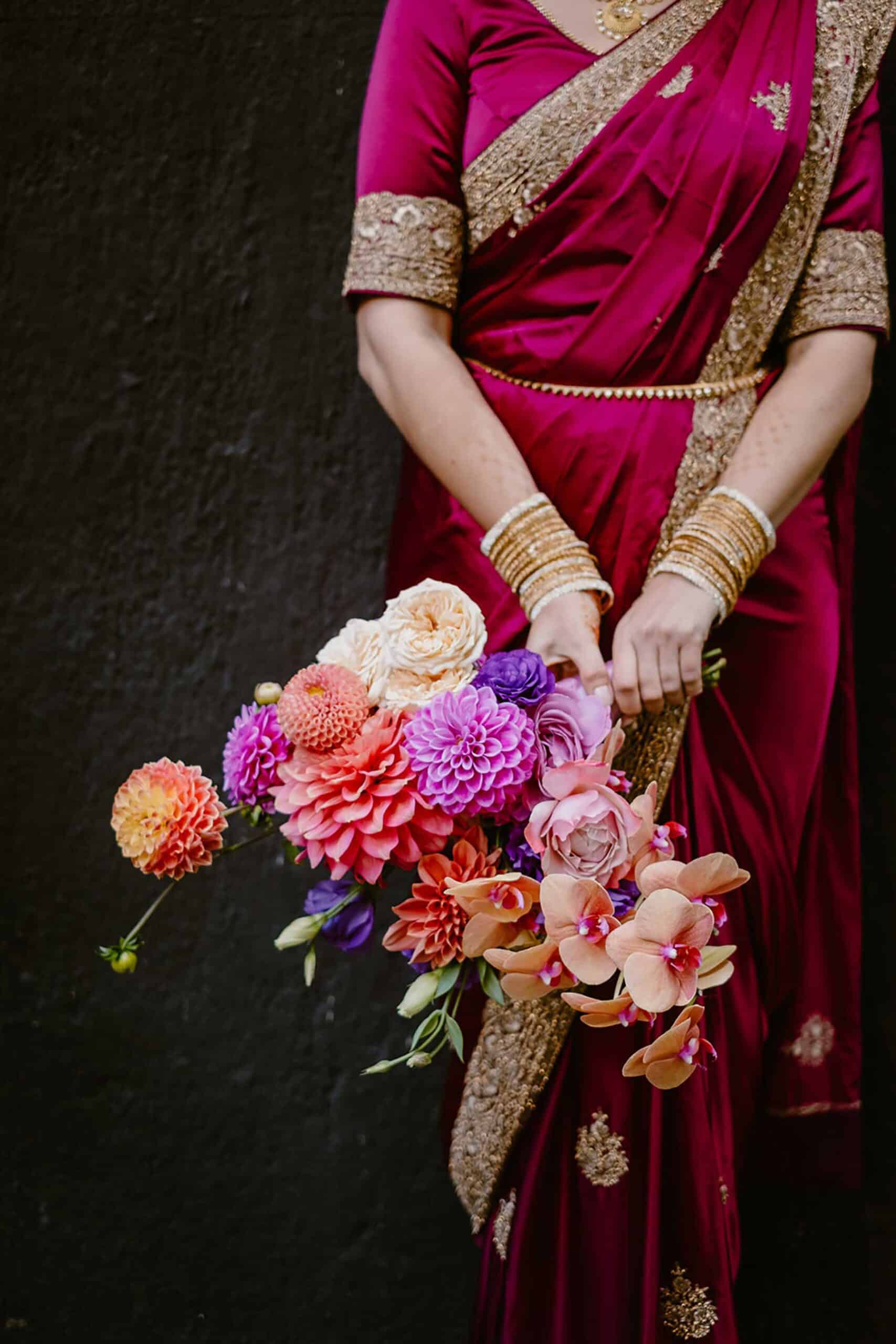 bride in red sari with colourful bridal bouquet