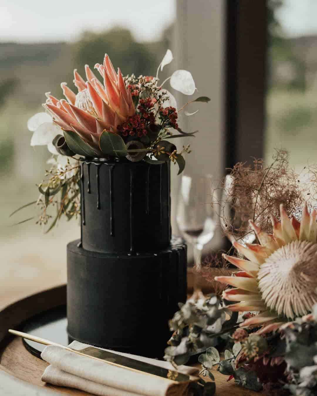 black wedding cake with king protea topper